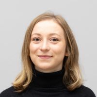 Myriam Bott – UI/UX Engineer: Lächelnde Frau mit schulterlangen, gewellten, blonden Haaren und schwarzen Rollkragenpulli.