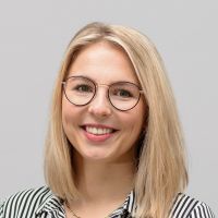 Julia Berg - Customer Success Manager: Smiling woman with blonde bob and thin, black, slightly rounded glasses.