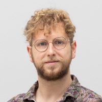 Daniel Tepavac – Data Assistant: Mann mit blonden Locken; rotblonden Bart; blauen Augen und dünner, eckiger Brille